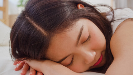 Fototapeta premium Asian woman dreaming while sleeping on bed in bedroom, Beautiful japanese female using relax time lying on bed at home. Lifestyle women using relax time at home concept.