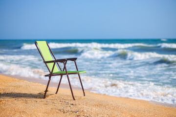 one green folding chair on the sea beach