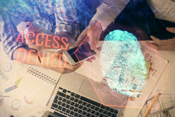 Double exposure of fingerprint hologram and man and woman working together holding and using a mobile device. Security concept
