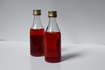 Red liquid in bottles on white background