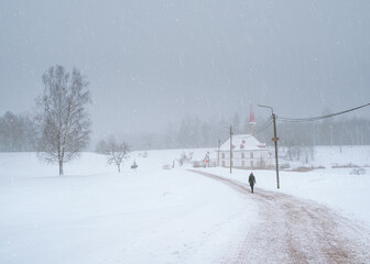 A walking silhouette on a winter road. White snowy landscape with old Maltese palace in beautiful natural landscape.