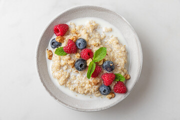 Quinoa porridge with fresh berries, nuts and mint in a bowl on white background. top view. healthy breakfast