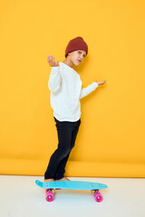 Cheerful little kid in a white sweater skateboard entertainment isolated background