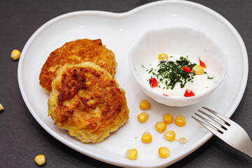 Delicious catlets on a plate with sauce of sour cream and greens close-up.