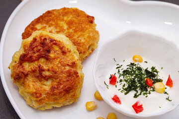 Delicious catlets on a plate with sauce of sour cream and greens close-up.