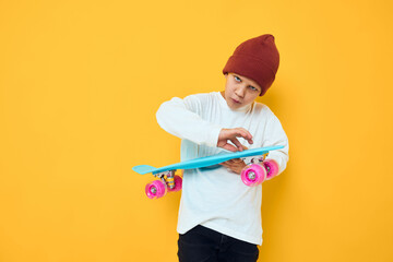 Cheerful little kid in a red hat skateboard in his hands studio posing