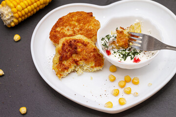 Delicious catlets on a plate with sauce of sour cream and greens close-up.