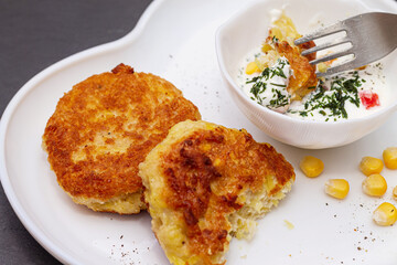 Delicious catlets on a plate with sauce of sour cream and greens close-up.