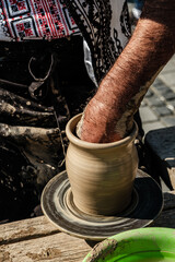 Hands of a potter shaping a clay pot on a potter wheel