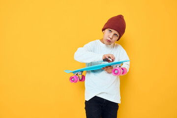 Cheerful little kid casual blue skateboard yellow color background