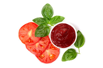 Ketchup (tomato paste) in a saucepan with basil leaves and tomato slices on a white background.