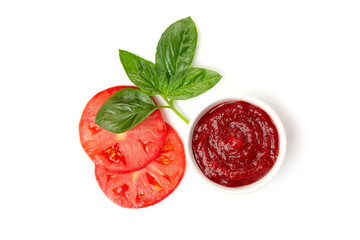Ketchup (tomato paste) in a saucepan with basil leaves and tomato slices on a white background.