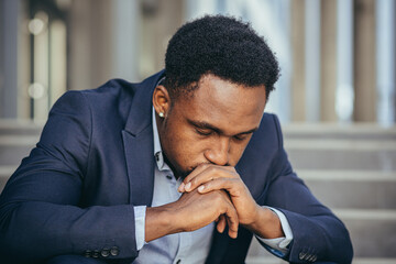 African american businessman in business suit frustrated got bad news from work, fired depressed sitting on stairs, close-up portrait photo