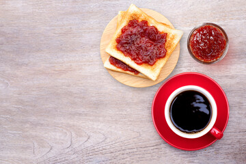 Tasty toast with red jam and cup of coffee isolated on rustic wooden table background. Top view. Flat lay. Copy space.