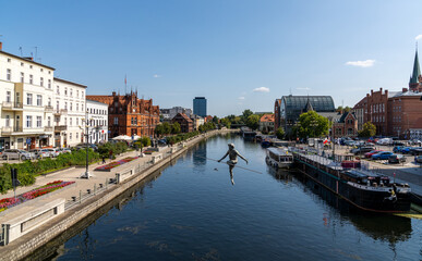 Fototapeta na wymiar view of the historic waterfront warehouses and buildings on the Brda River in downtown Bygdoszcz with the Crossing the River sculpture in the foreground