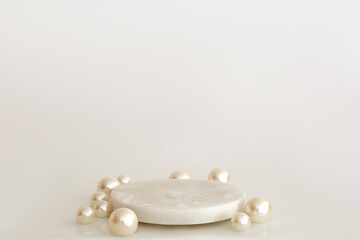White marble podium with pearls and water drops on the white background. Podium for product, cosmetic presentation. Creative mock up. Pedestal or platform for beauty products.