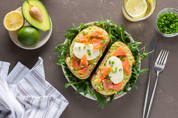 Delicious hearty breakfast, sandwiches with avocado paste, salmon and mozzarella on a plate with arugula and pea sprouts