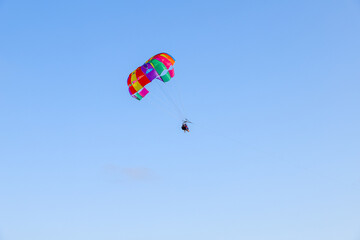 Parachute parasailing of tourists on a sunny day, adventure background with clear sky with no clouds
