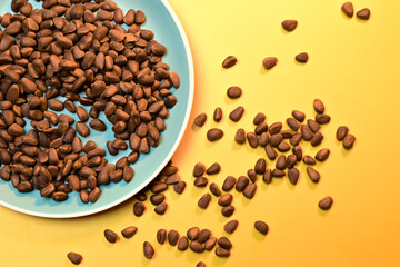 pine nuts scattered on a plate on a yellow background