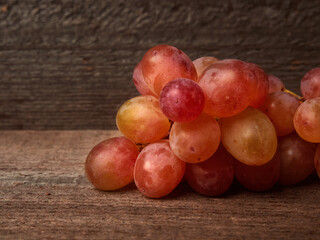 Letters of fresh ripe red grapes on a wooden textured surface. Ancient style, beautiful background with a branch of blue grapes. Red grapes.