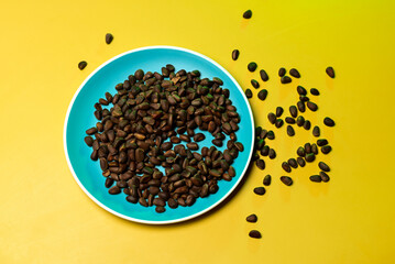 pine nuts scattered on a plate on a yellow background