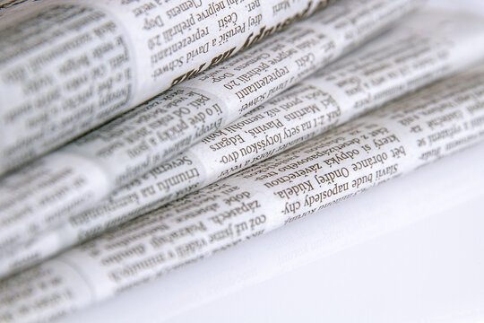 Stacked piles of newspapers on a white background. Close-up.