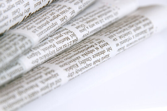 Stacked piles of newspapers on a white background. Close-up.