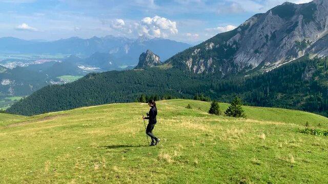Female hiker in the Alps of Allg&auml;u Bavaria Germany with hiking ploes with mountain panorama in the background, Hochalp close to Pfronten