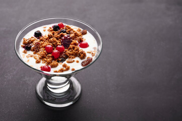 Cup of fresh yogurt with cereals and fruits over grey background