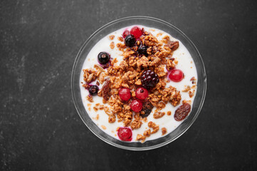 Cup of fresh yogurt with cereals and fruits over grey background