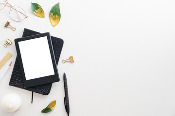 E book digital tablet mockup, paper notebook, pen, candle and green leaves on white desk table....