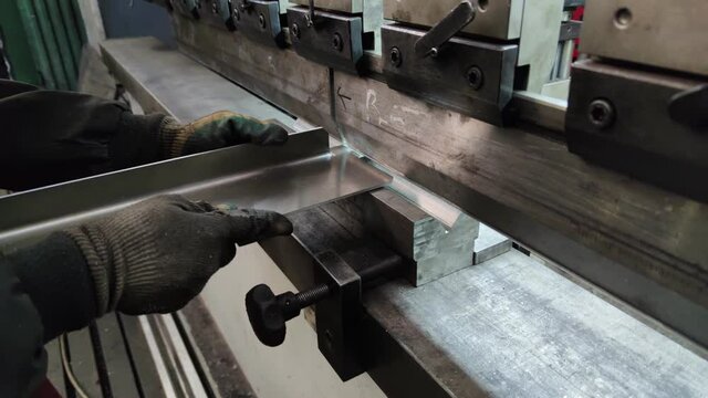 Bending a thick sheet of metal on a bending machine, close-up. Machine operator bends a sheet metal.