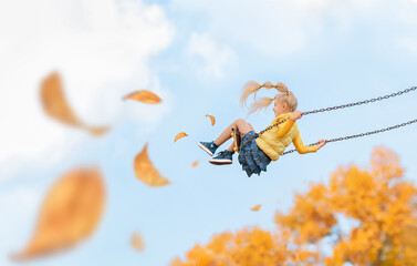 Happy child girl rides on a swing in the fall. - obrazy, fototapety, plakaty