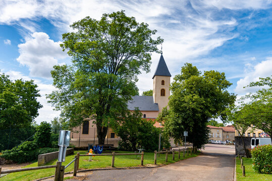 Vue sur un petit village avec son église Saint-Rémy de Scy à Scy-Chazelles sur un ciel bleu et des arbres