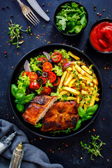 Tasty grilled ribs with french fries and fresh vegetables on wooden table
