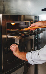 chef cook putting pizza in electric oven in a pizzeria