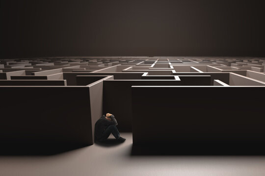 Unidentifiable man cowering in the entrance of a dark brown maze. Depression concept, hopelessness.