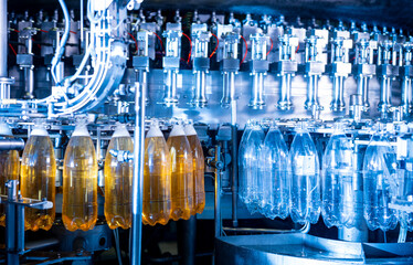 Automatic filling machine pours water into plastic PET bottles at modern beverage plant.