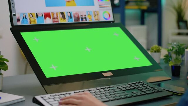 Close up of horizontal green screen at editing workplace. Woman photographer looking at chroma key with mockup template and isolated background, retouching pictures on computer app