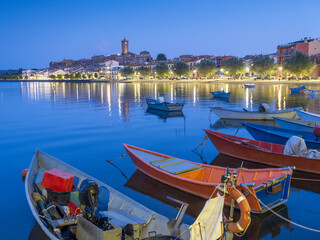 Fototapeta na wymiar night lights above blue lake and fishing boats in city Marta on lake Bolsena in Italy