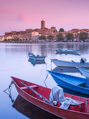 pink clouds above boats and city Marta on lake Bolsena in Italy