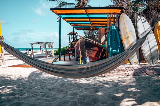 Hanging Empty Hammock With Boat And Canoe On Sand At Beautiful Mexican Beach Resort