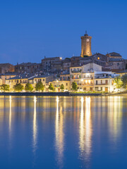 blue hour with golden lights of city Marta on lake Bolsena in Italy - obrazy, fototapety, plakaty