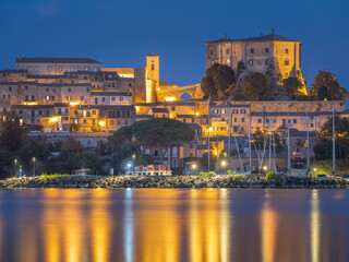 Fototapeta na wymiar Golden lights of city Capodimonte in twilight time on lake Bolsena in Italy