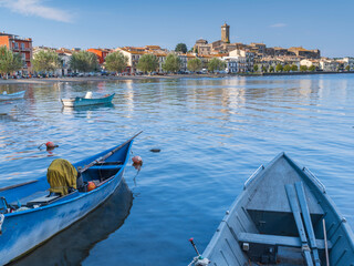 view through boats to city Marta on lake Bolsena in Italy - obrazy, fototapety, plakaty