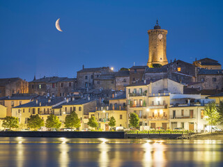 The Moon above city Marta on lake Bolsena in Italy in night lights
