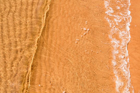 Close Up Of Small Wave Over Rippled Sand