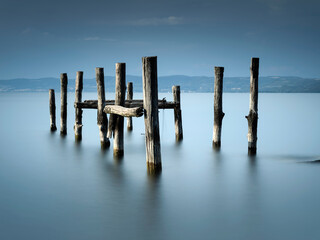 smooth water in long exposure and wooden trunk in it on lake Bolsena in Italy
