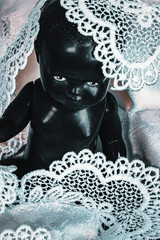 black doll covered in white lace