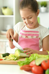 Obraz na płótnie Canvas Close up portrait of cute girl preparing delicious fresh salad in kitchen